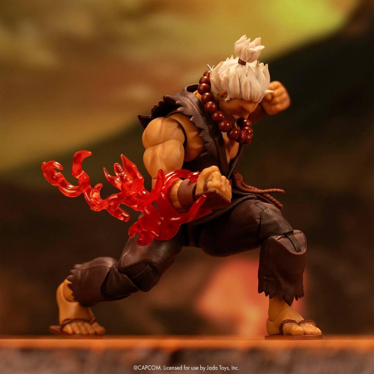 Figurine Akuma Jada Toys en position de fente, avec un effet d’énergie rouge autour du poing tendu