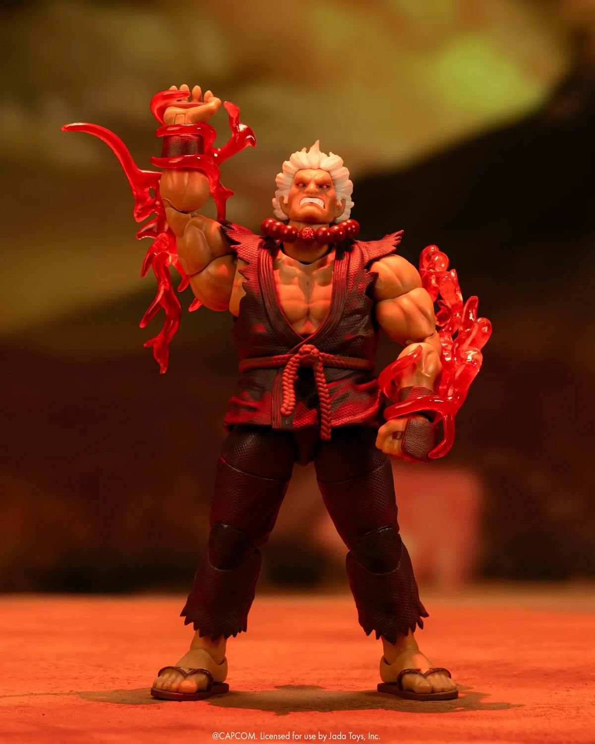 Figurine Akuma Jada Toys de face, un bras levé et des effets d’énergie rouges autour des avant-bras
