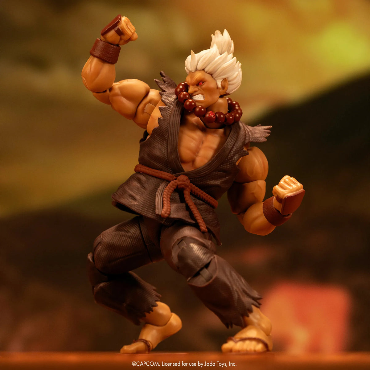 Figurine Akuma Jada Toys en posture de combat, poing levé, avec cheveux blancs et collier de perles rouges